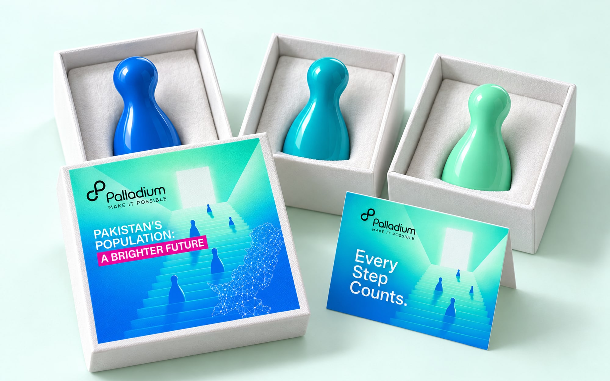Three small glossy pawns in blue, teal and mint, each in an open white gift box, with a printed lid and a card reading Every Step Counts