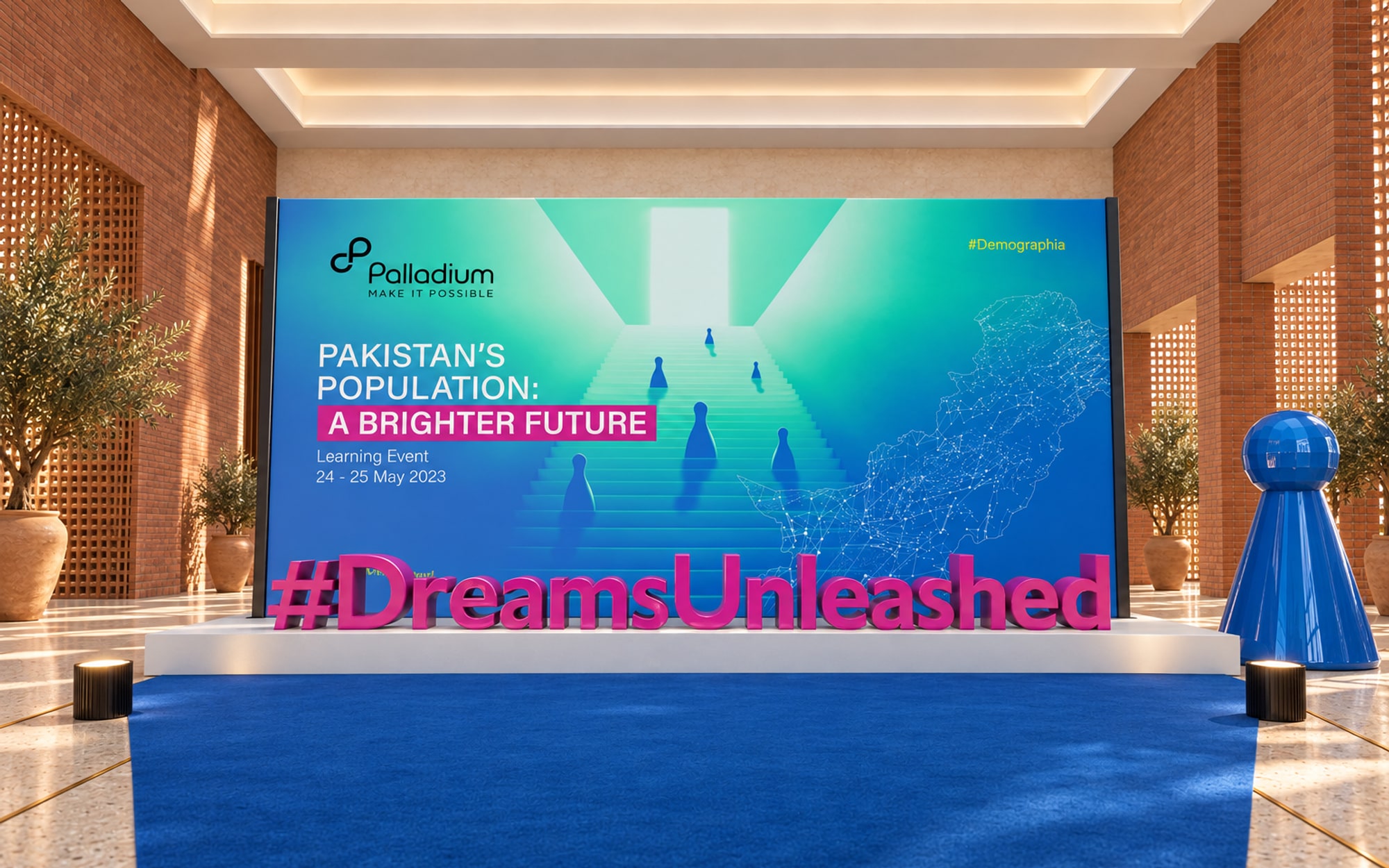 A media wall carrying the key visual with large magenta letters reading #DreamsUnleashed on a white plinth in front of it and a blue pawn sculpture beside it
