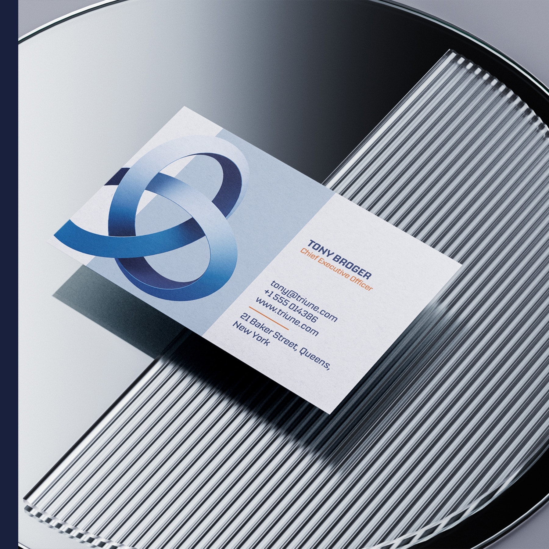 A Triune business card on a ribbed metal surface, the mark running off the left edge and the details ranged right